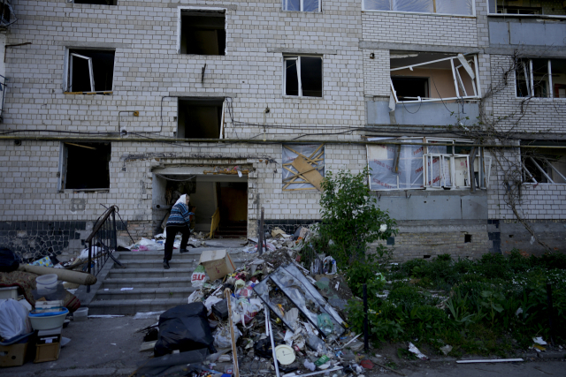 24일(현지시간) 우크라이나 보로디얀카 마을에서 한 주민이 포격으로 파괴된 자택 건물로 들어가고 있다. AP연합뉴스