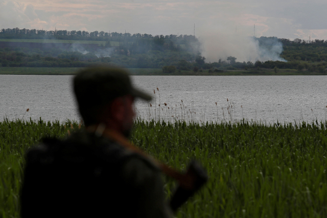 25일(현지시간) 우크라이나 동부 도네츠크주의 노볼루한스케 외곽에서 한 친러시아 반군 대원이 치솟는 포연을 바라보고 있다. 연합뉴스