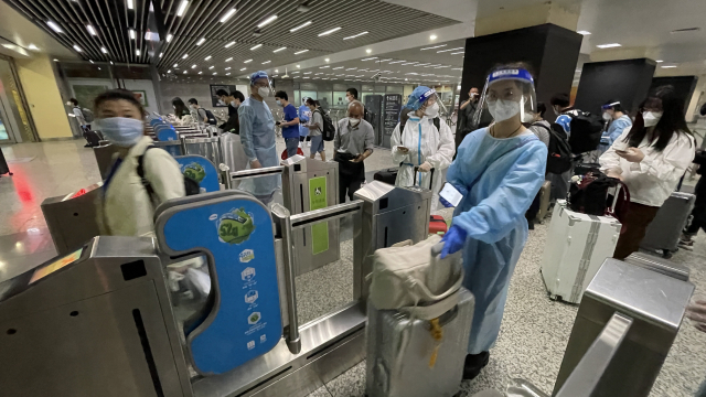 지난 22일 중국 상하이 전철 10호선 훙차오기차역의 승객들이 개찰구를 나서고 있다. 고속철을 타고 먼 곳으로 이동하려는 승객 중 일부는 코로나19 감염을 막기 위해 방호복을 입고 있다. 연합뉴스
