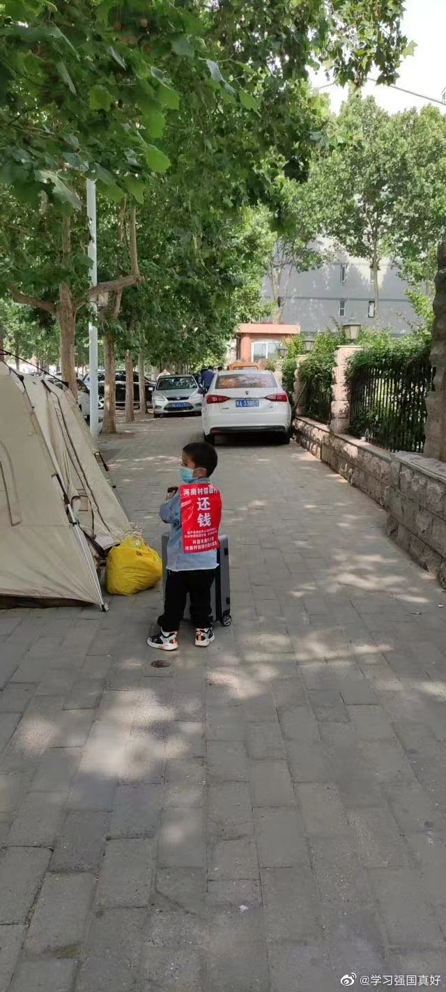 허난성 정저우 은행보험감독관리위원회 앞에 농성중인 시위대의 한 어린이가 '돈을 돌려달라'고 적힌 글을 등에 매달고 있다. 웨이보 캡쳐