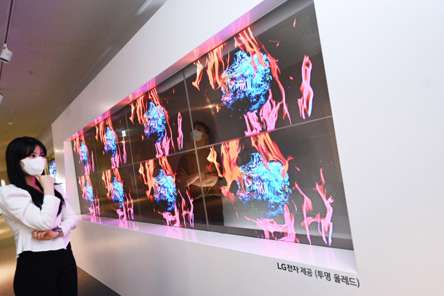 LG전자 모델이 31일 서울 동대문디자인플라자(DDP)에 전시된 투명 올레드 사이니지로 예술 작품을 감상하고 있다. 사진제공=LG전자