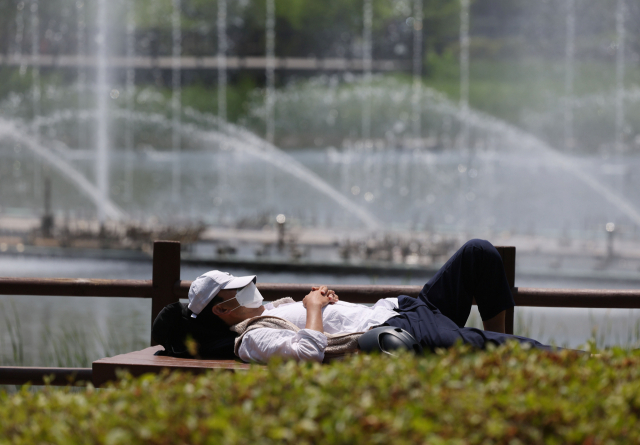 초여름 날씨가 지속되는 31일 오후 서울 보라매공원에서 한 시민이 뙤약볕에 누워 잠시 잠을 청하고 있다. 연합뉴스
