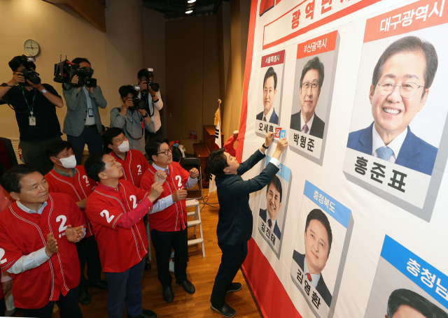 이준석 국민의힘 대표와 지도부가 2일 새벽 국회 도서관 대강당에 마련된 지방선거 개표 상황실에서 당선이 유력시되는 단체장 후보 사진 밑에 스티커를 붙이는 세리머니를 하고 있다. 성형주 기자