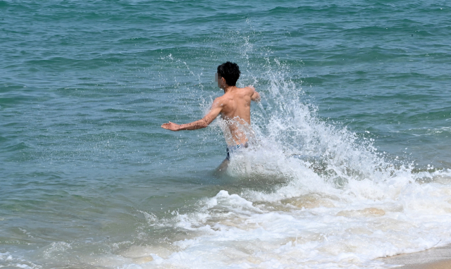 2일 강원 강릉시 경포해변에서 한 젊은 관광객이 바닷물에 뛰어들어 무더위를 식히고 있다. 연합뉴스