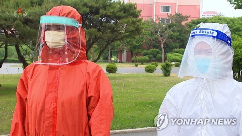 북한에 코로나19 확산세가 가파른 가운데 방역요원(오른쪽)이 영문으로 'Face Shield'(안면보호구)라고 적힌 안면보호구를 착용하고 있다./연합뉴스