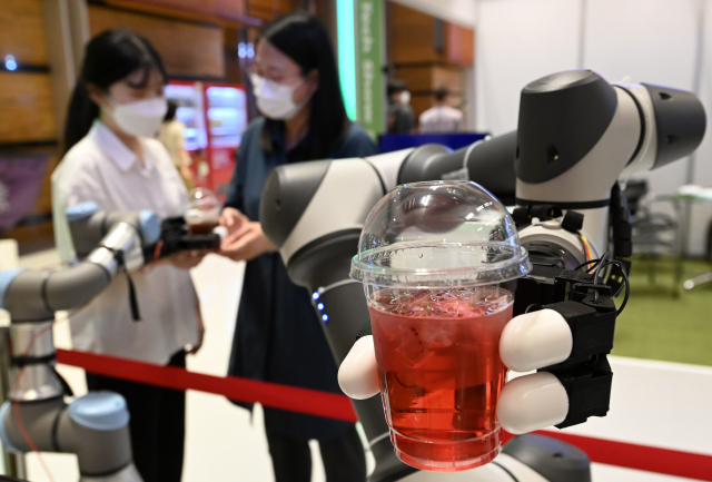 8일 서울 강남구 삼성동 코엑스에서 열린 '제11회 스마트테크 코리아' 행사에서 관계자들이 핑거 로봇을 이용해 음료를 서빙하고 있다. 성형주기자