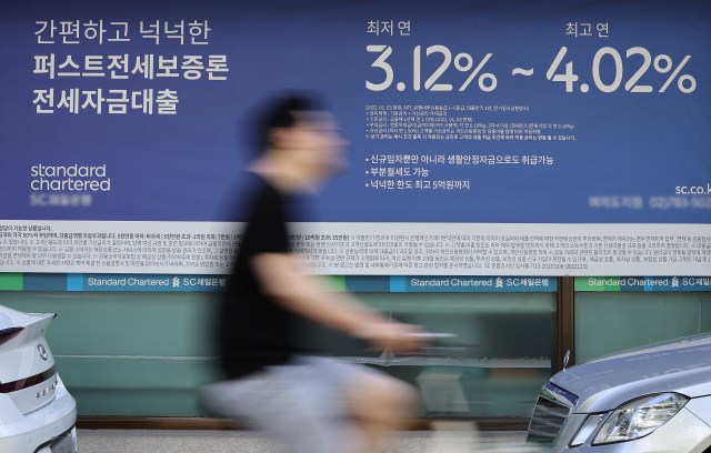 지난 6일 서울의 한 시중은행 대출 광고 안내판 앞을 시민들이 지나치고 있다. 연합뉴스