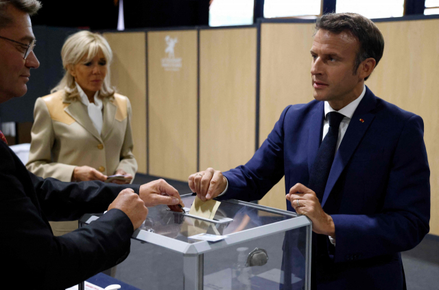 에마뉘엘 마크롱(오른쪽) 프랑스 대통령과 부인 브리지트 마크롱(가운데)이 12일(현지 시간) 르투케에 있는 투표소에서 투표하고 있다. AFP연합뉴스
