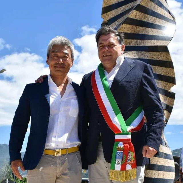 이탈리아에서 활동하는 조각가 박은선(왼쪽) 씨와 알베르토 스테파노 조반네티 피에트라산타 시장이 현지 고속도로 교차로에 영구 설치된 박 작가의 11m 대작 ‘무한한 기둥’ 앞에서 포즈를 취하고 있다. 사진 제공=박은선 작가