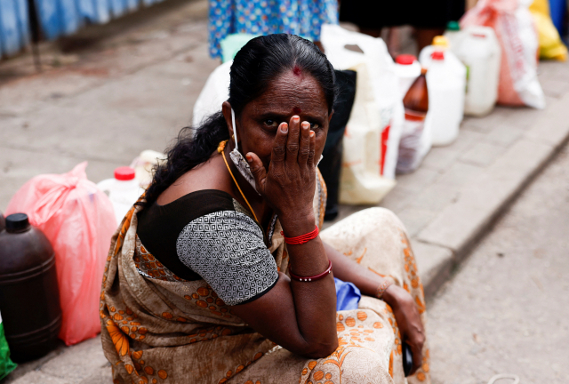 17일(현지시간) 최악의 경제 위기를 겪고 있는 스리랑카 콜롬보에서 한 여성이 등유를 사기 위해 인도에 앉아 줄 서고 있다. 연합뉴스
