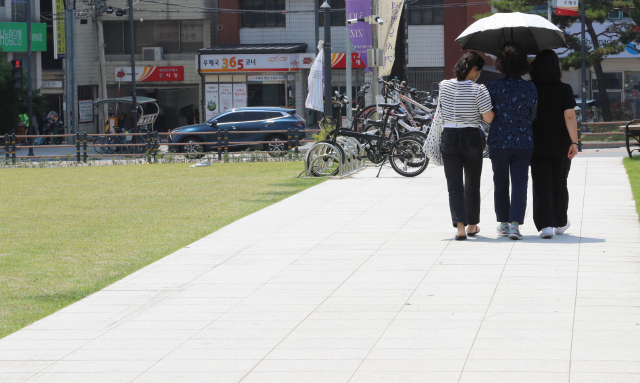 폭염주의보가 내려진 21일 오후 시민들이 양산을 쓴 채 청주시 거리를 걷고 있다. 연합뉴스