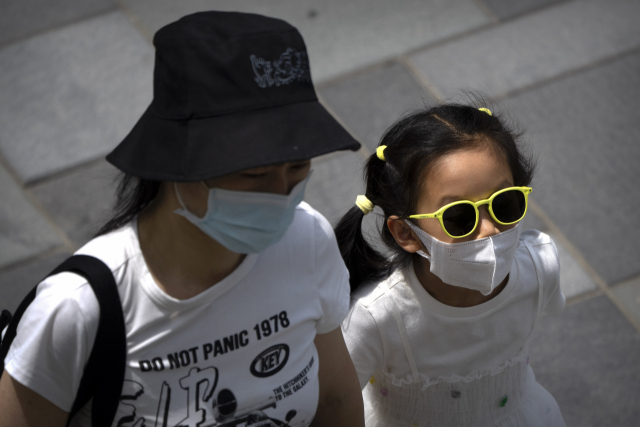 마스크를 쓴 여성과 소녀가 25일 베이징의 한 쇼핑가를 걷고 있다. AP연합