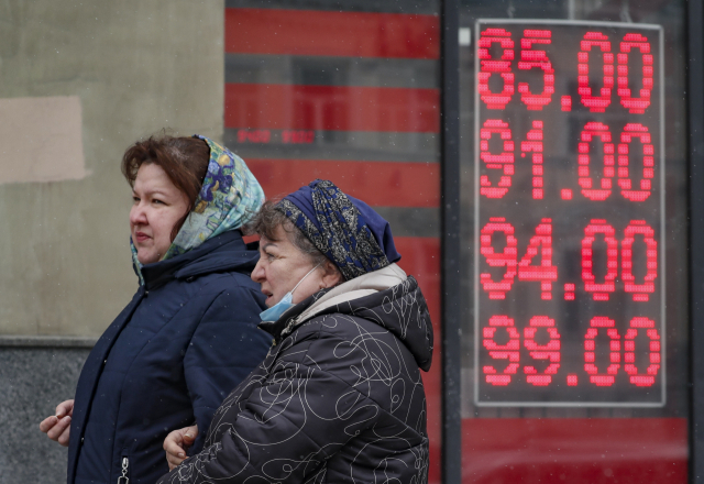 러시아 수도 모스크바 시내에서 지난달 31일(현지 시간) 행인들이 환전소의 환율 안내판 앞으로 지나가고 있다. EPA연합뉴스