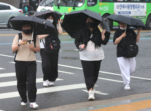 서울에 강풍을 동반한 소나기가 내린 28일 오후 서울 마포구 지하철 홍대입구역 인근 횡단보도에서 시민들이 비바람을 맞고 있다. 연합뉴스