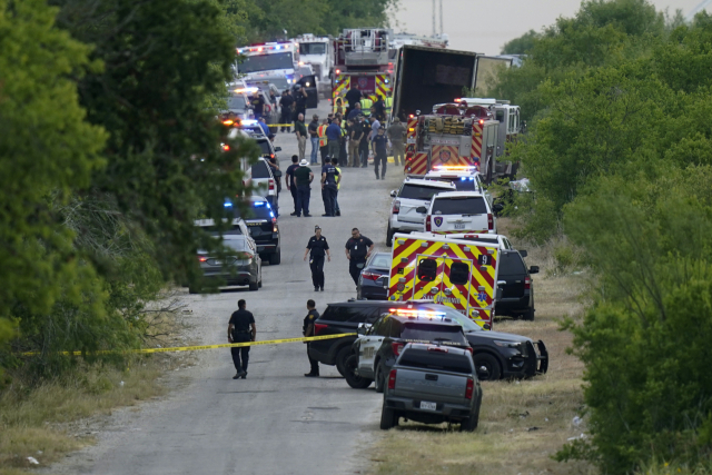 27일(현지시간) 미국 텍사스주 샌안토니오 남서부 외곽에서 경찰들이 시신이 무더기로 발견된 대형 트레일러 근처에서 일하고 있다. AP연합뉴스