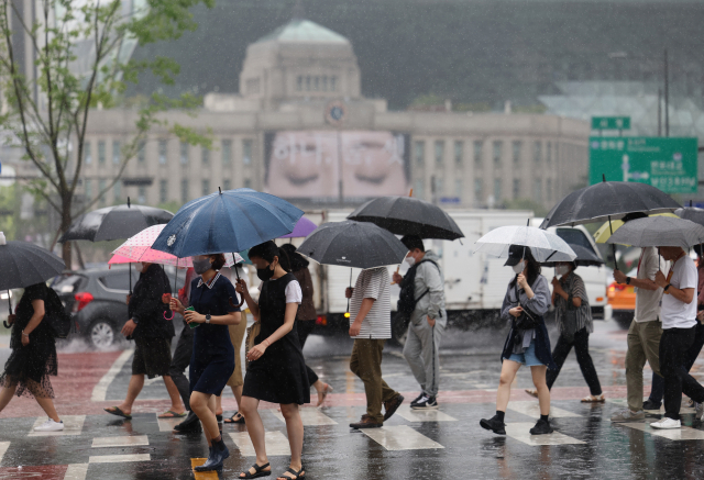 서울지역에 장맛비가 내린 29일 오후 서울도서관 인근에서 시민들이 우산을 쓴 채 횡단보도를 건너고 있다. 연합뉴스