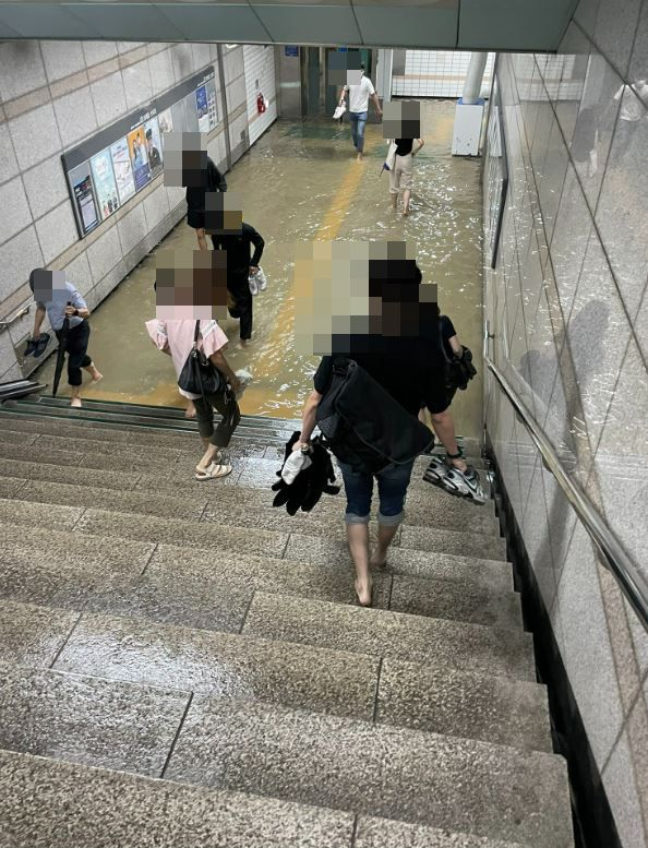 경기 수원 세류역의 지하통로가 물에 잠겨 출근길 시민들이 바지를 걷고 맨발로 이동하는 모습이 화제를 모으고 있다. 트위터 캡처