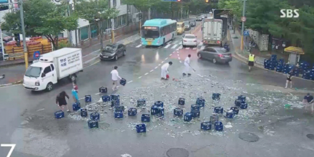 지난 29일 강원도 춘천시 퇴계동의 한 거리에서 좌회전 하던 트럭에서 맥주병 2000여개가 쏟아졌다. 이를 본 시민들이 현장을 정리하고 있다. SBS 캡처