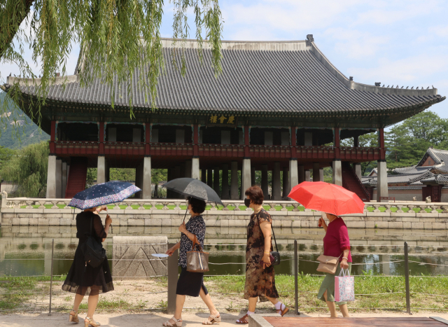 전국적으로 폭염경보가 발표되며 서울 한낮 기온이 33도까지 치솟은 3일 서울 종로구 경복궁에서 시민들이 양산을 쓰고 걷고 있다. 연합뉴스