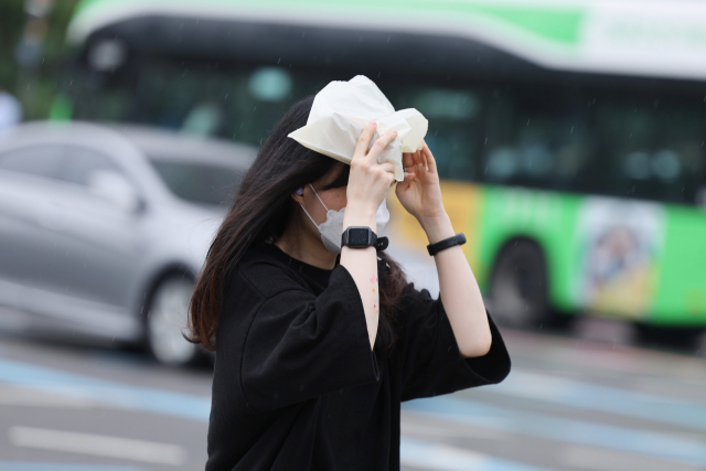 한 시민이 4일 오후 서울 종로구 광화문네거리에서 비닐봉투로 비를 막으며 발걸음을 재촉하고 있다. 연합뉴스