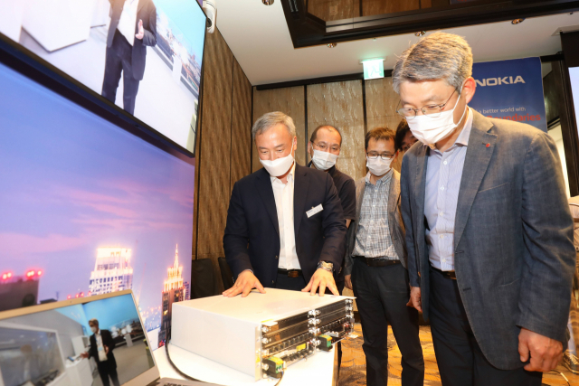 권준혁(맨 오른쪽) LG유플러스 네트워크부문장이 김우조(맨 왼쪽) 노키아 전무로부터 노키아가 개발한 신형 기지국 장비에 대해 설명을 듣고 있다. 사진제공=LG유플러스