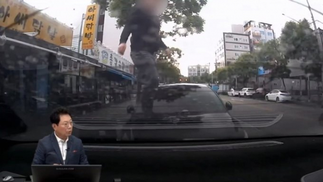 지난달 6일 오후 6시쯤 경기도 오산 한 노상 주차장 옆 인도에서 한 행인이 길을 걷다가 난데없이 주차된 차량 위로 뛰어올랐다. 유튜브 캡처