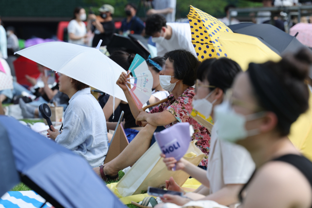 무더운 날씨를 보인 7일 오후 서울 시청광장에서 열린 '참신한 북 콘서트\'에서 관람객들이 우산을 쓴 채 부채질을 하고 있다. 2022.7.7 hwayoung7@yna.co.kr (끝)