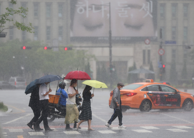 서울지역에 장맛비가 내린 지난달 29일 오후 서울도서관 인근에서 시민들이 우산을 쓴 채 횡단보도를 건너고 있다. 연합뉴스