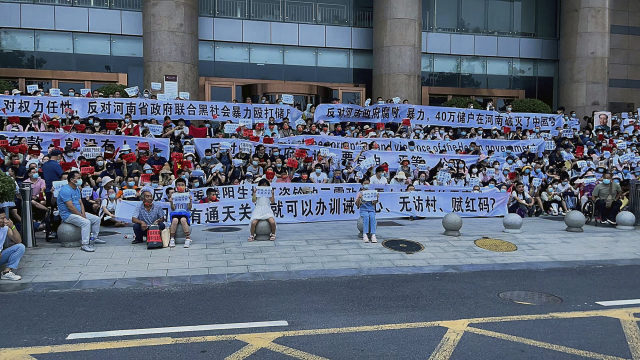 중국 허난성 정저우에 있는 중국 인민은행 정저우 지점 입구에서 10일 예금 인출을 요구하는 사람들이 현수막을 들고 구호를 외치고 있다. AP연합