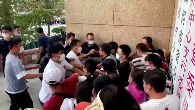 중국 허난성 정저우의 중국 인민은행 정저우 지점 앞에서 10일 예금 동결에 항의하는 시위대와 사복 보안 요원들이 몸싸움을 벌이고 있다. 로이터연합