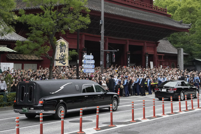 아베 신조 전 일본 총리의 시신을 실은 운구차가 12일 도쿄 조조지 사찰을 나서자 수백 명의 시민이 운집해 작별 인사를 하고 있다. AP연합뉴스