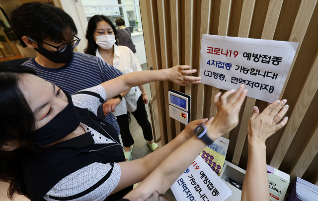 13일 서울의 한 보건소 건강센터에서 보건소 관계자가 코로나19 백신 4차 접종 관련 안내문을 부착하고 있다. 연합뉴스