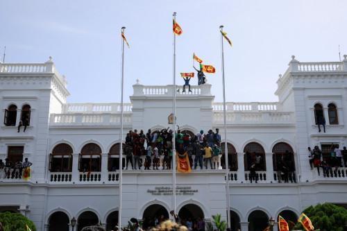 13일(현지시간) 스리랑카 반정부 시위대가 수도 콜롬보에 있는 라닐 위크레메싱게 총리 집무실 건물 꼭대기에 서서 국기를 흔들고 있다. 로이터연합뉴스