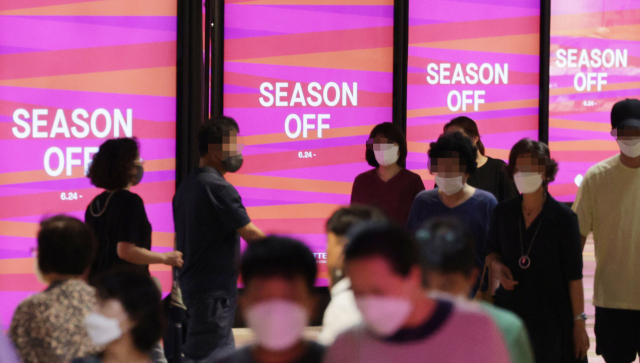 지난 달 24일 서울 시내 한 백화점에 설치된 전광판 앞으로 방문객들이 지나가고 있다. 코로나 엔데믹 효과에 백화점 세일 기간 의류 매출이 크게 늘었다./연합뉴스