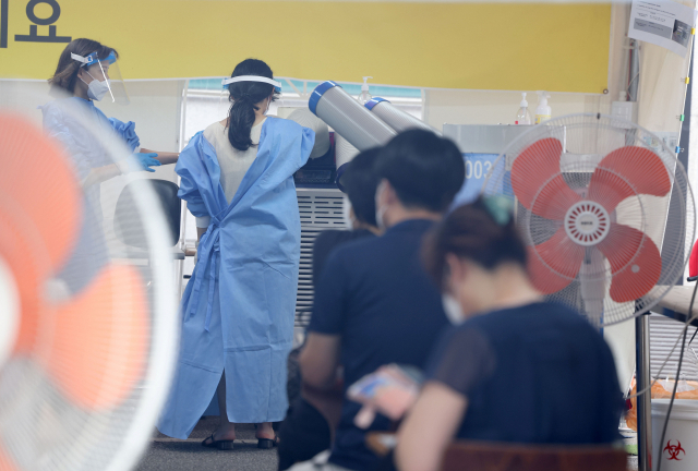 지난 17일 오후 서울 강남구보건소 코로나19 선별진료소에서 의료진이 냉풍기로 더위를 식히고 있다. 연합뉴스