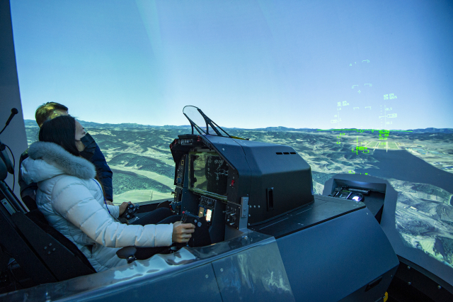 국방부 취재진이 지난해 2021년 2월 24일 경남 사천에 한국항공우주산업(KAI)이 마련한 ‘KF-21보라매’전투기 연구개발 및 제작시설을 방문해 ‘조종성평가 시뮬레이터(HOS)’에 앉아 전면 스크린에 펼쳐진 가상공간을 배경으로 비행연습을 체험하고 있다. /사진제공=KAI