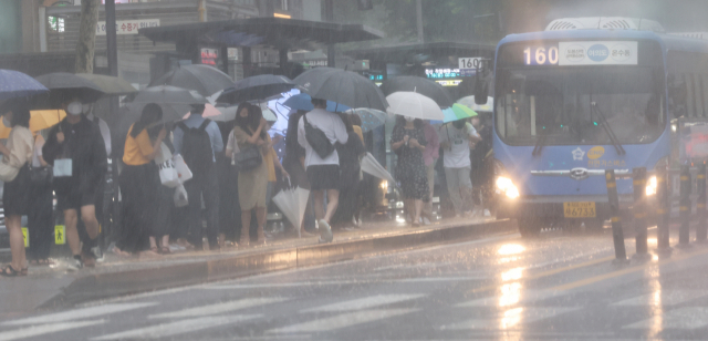 서울 시내 정류장에서 시민들이 비를 피하며 버스를 기다리고 있다. 연합뉴스