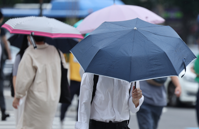가벼운 소나기가 내린 지난 4일 우산을 쓴 시민들이 서울 종로구 광화문네거리에서 이동하고 있다. 연합뉴스