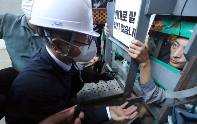 이정식 고용노동부 장관이 19일 오후 경남 거제시 아주동 대우조선해양 옥포조선소 파업 현장을 방문해 조선소 독 화물창 바닥에 가로, 세로, 높이 각 1ｍ 철 구조물 안에서 농성 중인 유최안 금속노조 거제통영고성 조선하청지회 부지회장과 면담하고 있다. 연합뉴스