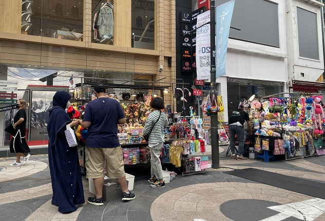 이달 21일 오후 외국 관광객들이 명동 메인 상권에 위치한 노점상에서 물건을 구매하고 있는 모습.