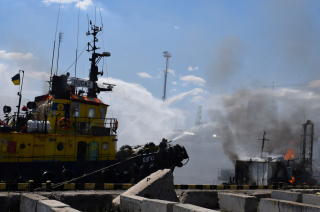23일(현지시간) 러시아군이 쏜 미사일 공격을 받아 우크라이나 오데사 항구 일부가 불타고 있는 가운데 소방관들이 불길을 진압하고 있다. 로이터연합뉴스
