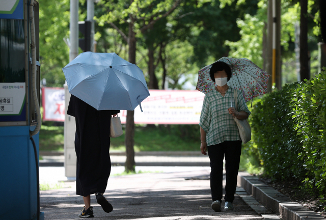 25일 오전 서울 여의도 국회대로에서 시민들이 양산을 쓴 채 이동하고 있다. 연합뉴스