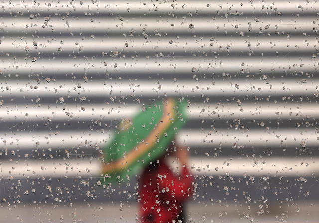 소나기가 내린 22일 오후 서울시청 인근에서 한 시민이 우산을 쓴 채 이동하고 있다. 연합뉴스