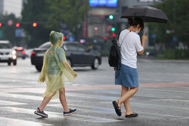 한 어린이가 지난 22일 서울광장 인근에서 우비를 입은 채 소나기를 맞으며 이동하고 있다. 연합뉴스
