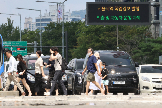 폭염경보가 내린 29일 오후 시민들이 서울 영등포구 여의대로에서 더위로 아지랑이가 피어오르는 도로를 건너고 있다. 연합뉴스