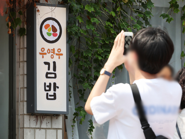 지난 4일 오전 드라마 '이상한 변호사 우영우' 촬영지인 경기도 수원시 팔달구 행궁동의 한 식당에서 시민들이 사진을 찍고 있다. 연합뉴스