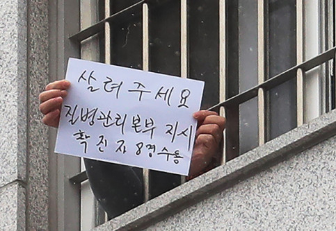 지난해 12월 서울 동부구치소에서 한 수용자가 확진자 과밀수용 등 불만 사항을 직접 적어 취재진을 향해 들어 보이고 있다. 연합뉴스