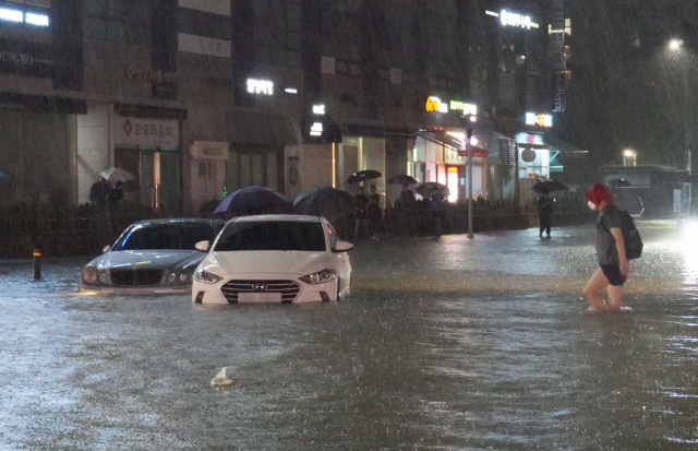 지난 8일 밤 서울 강남구 대치동 은마아파트 부근 도로와 인도가 물에 잠기면서 차량과 보행자가 통행하는 데 불편을 겪고 있다. 연합뉴스