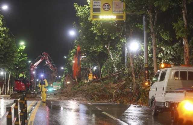 폭우가 내린 9일 오전 서울 서초구의 한 도로에 산사태가 발생해 일부 차선 통제와 복구 작업이 이뤄지고 있다. 연합뉴스