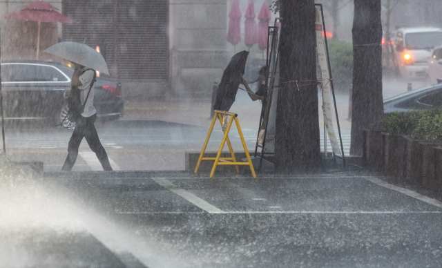 지난 8일 오후 서울 여의도에서 퇴근길을 나선 시민들이 하늘에서 쏟아붓는 비를 피하기 위해 사투를 벌이고 있다. /연합뉴스